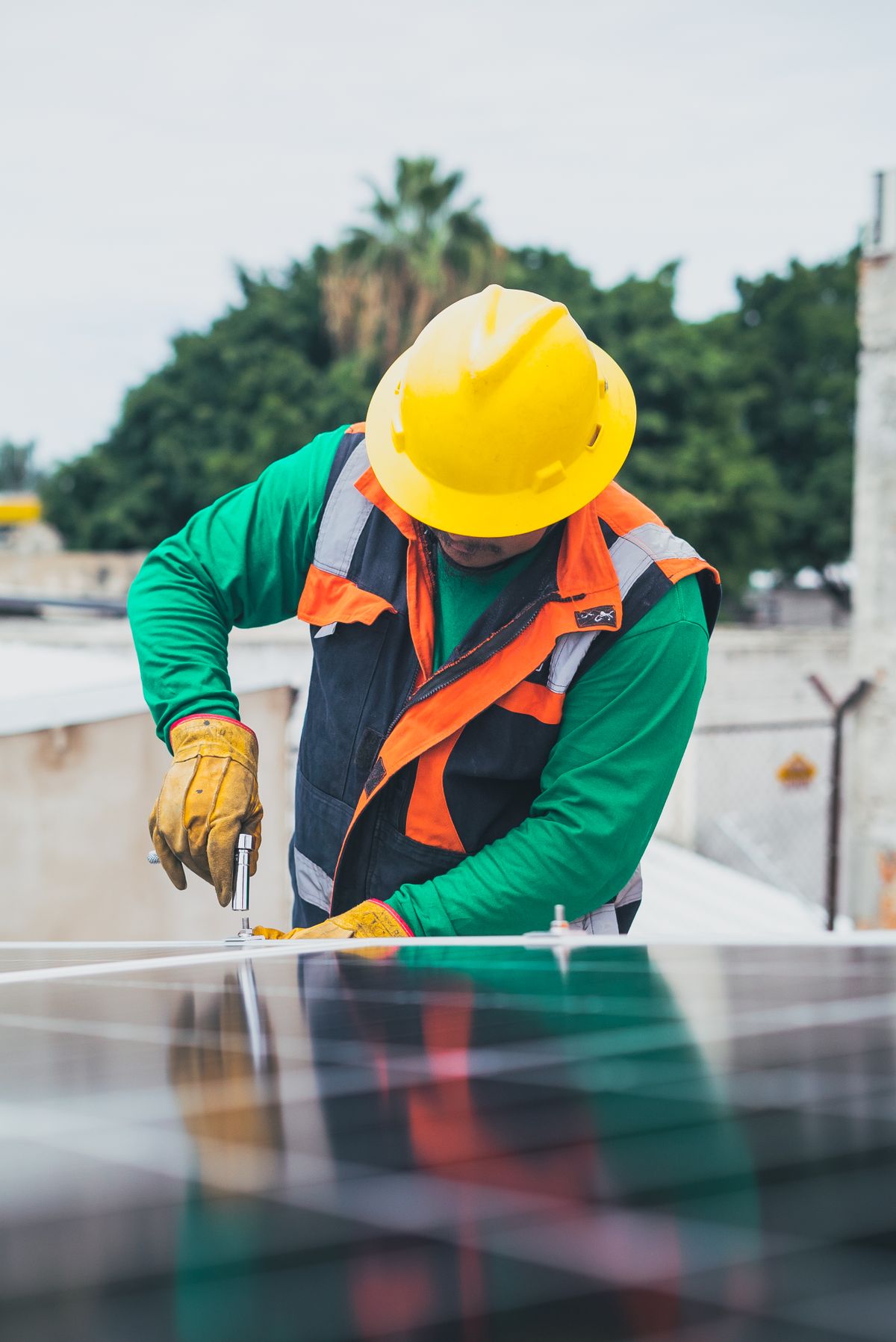 Technician in a hard hat servicing solar panels on a rooftop