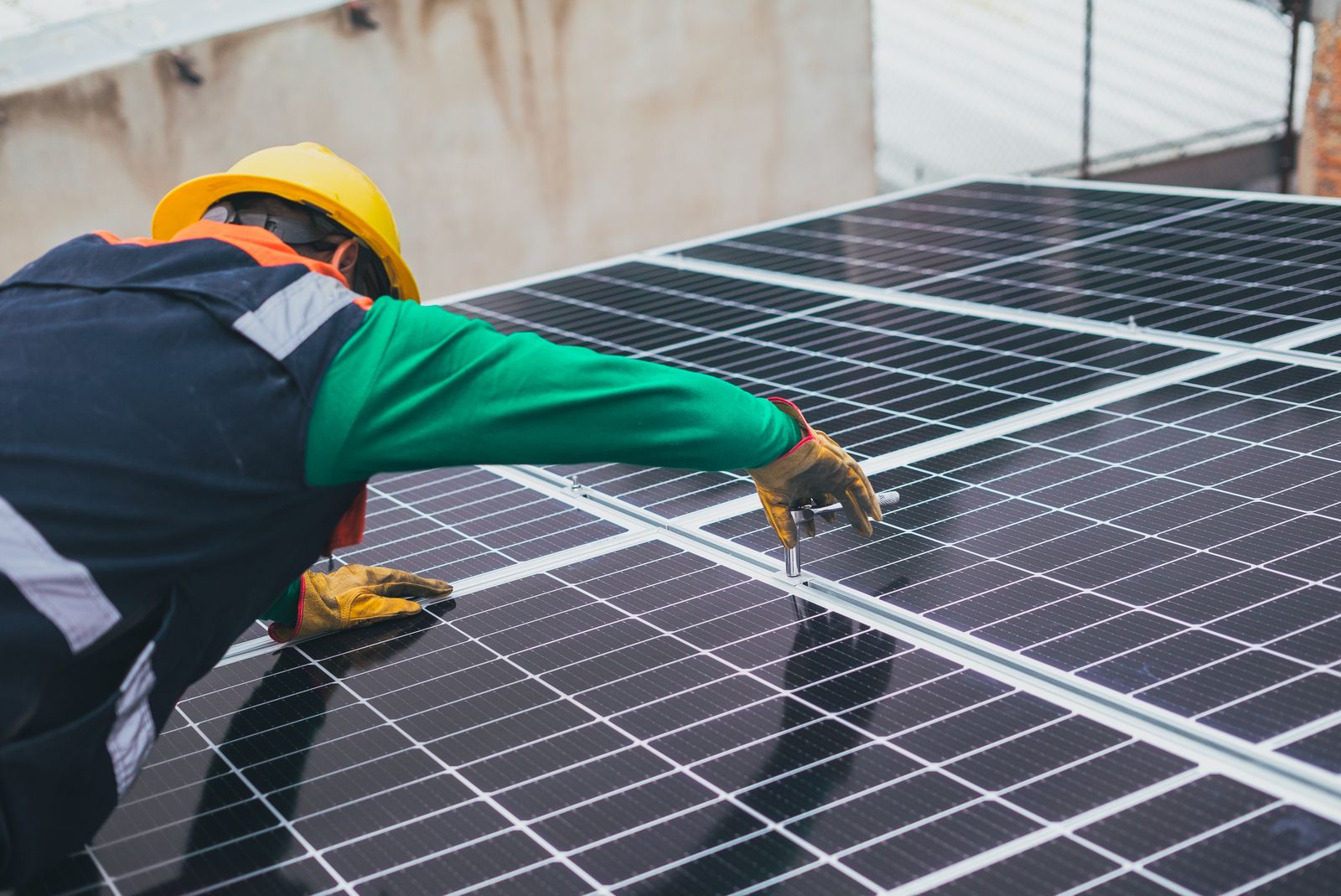 Technician in a hard hat installing solar panels on a rooftop